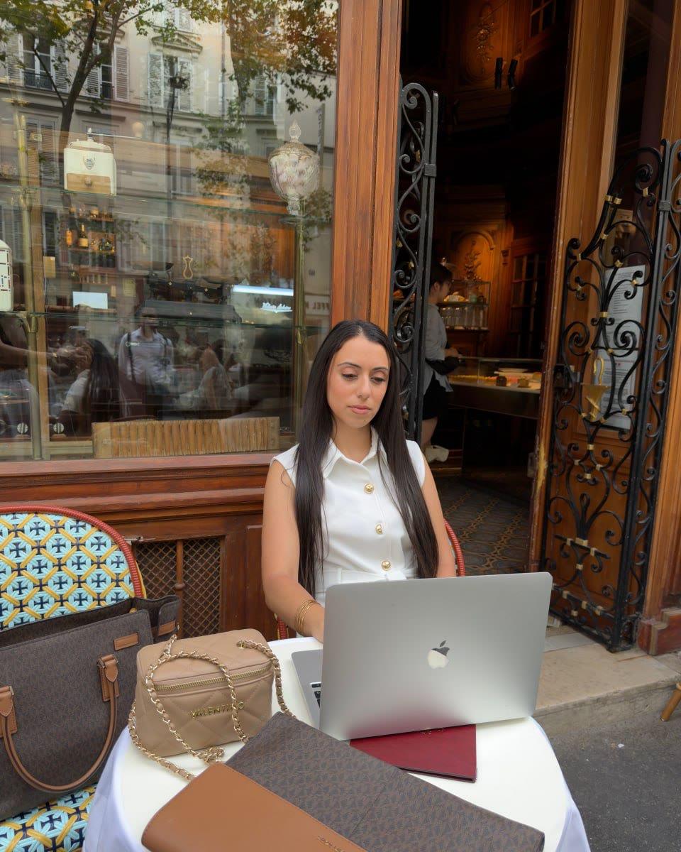 Adraa working from a cafe table in Paris, laptop open in front of her.